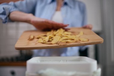 Kadın gübre kutusuna yiyecek kırıntıları atıyor. Sorumluluk sahibi bir kadın organik atıkları fermantasyon için bir bokashi kabında geri dönüştürüyor. Sürdürülebilir yaşam tarzı kavramı