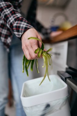 Female hand put organic food waste in a compost bin. The cook throwing peels in a bokashi container for decomposition. Sustainability concept clipart