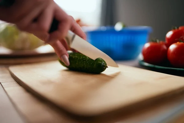 料理人は木の板の上に鋭いナイフでキュウリを切って閉じます 朝ご飯のために健康的なグリーンサラダを作る女性 — ストック写真