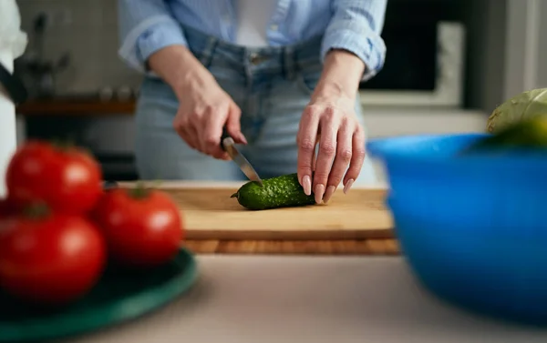 木の板にキュウリを切る女性の手 朝の野菜サラダの準備をする女 — ストック写真