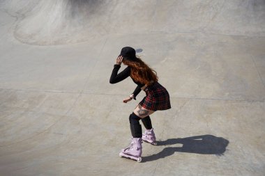 Beton bir havuzda patenci kadın paten kayıyor. Saldırgan buz patenci kız yazın kaykay parkında geziyor.