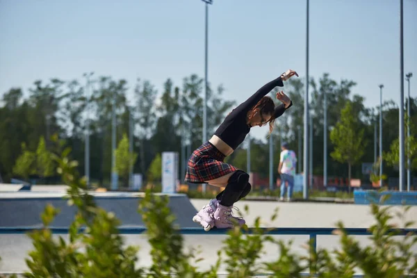 スケートパークのレールの上で若いローラーブラダー女性研削 クールな積極的なインラインスケーターは 具体的な都市公園で粉砕トリックを実行します — ストック写真