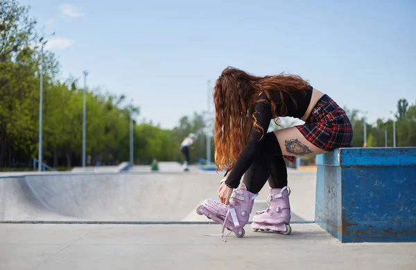 在一个混凝土滑板公园里 年轻漂亮的女滑板手穿着有侵略性的内联滑板 运动员们在城市公园准备乘坐轮滑刀片 — 图库照片