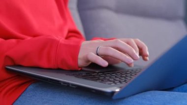 Evde dizüstü bilgisayarda kod yazan bir kadın programcı. Kanepede modern bir dizüstü bilgisayar üzerinde çalışan tanınmayan genç bir kadın, ellerine odaklanıyor. 