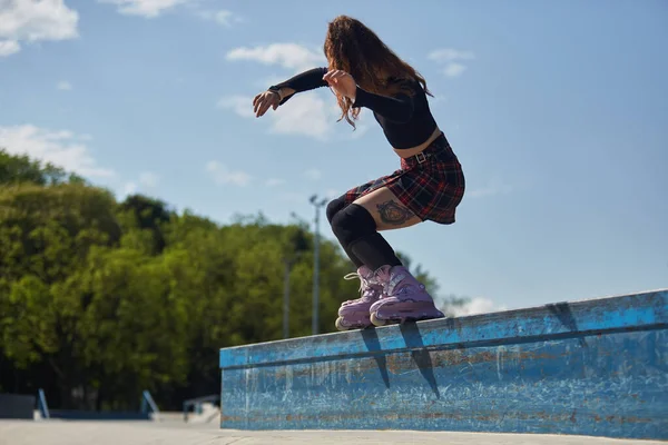 スケートパークの棚で若いローラーブラダー研削 クールな女性スケーターを身に着けています現代的な積極的なスケートバックを実行フルトルクグラインド屋外 — ストック写真