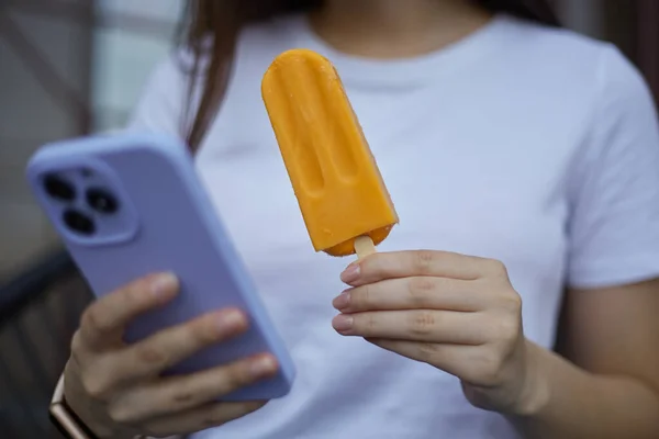 아이스크림을 보라색 전화를 알아볼 수없는 디저트를 즐기고 밖에서 스마트폰 사용하는 — 스톡 사진