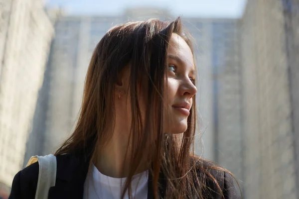 stock image Portrait of a beautiful young woman with long brown hair. Attractive white female in the city center near a high rise building in a sunny summer day.