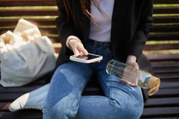 Νεαρή Γυναίκα Κάθεται Ένα Παγκάκι Ένα Έξυπνο Τηλέφωνο Και Γυάλινο — Φωτογραφία Αρχείου