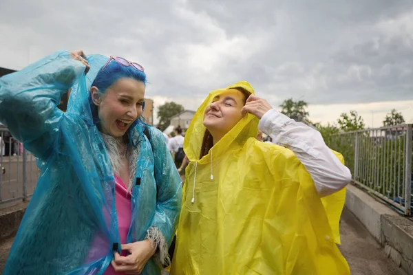 两个穿着雨衣的年轻女同性恋者玩得很开心 一对男女同性恋 双性恋和变性者在雨天在户外大笑的画像 — 图库照片