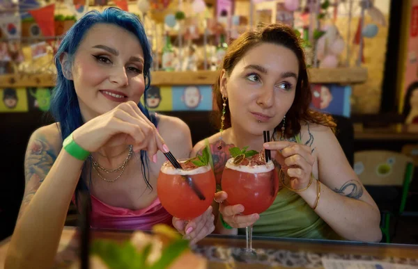 年轻的男女同性恋 双性恋和变性者夫妇在酒吧里享受着甜蜜的鸡尾酒 两个有纹身的年轻女子在酒吧里摆姿势喝酒 — 图库照片