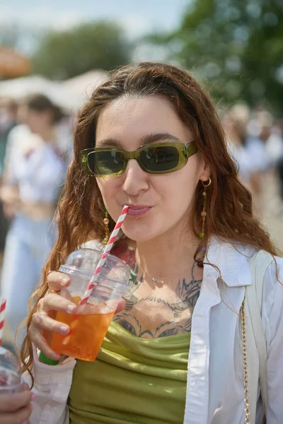 在夏天的节日里 戴着太阳镜的快乐的年轻女子喝着新鲜的橙色短跑鸡尾酒 在户外喝冷饮的女性 — 图库照片