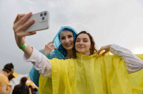 快乐的一对同性恋夫妇在雨中参加了一个夏季的节日 穿着雨衣的快乐的Lgbt女性摆出一副自拍的姿势 — 图库照片
