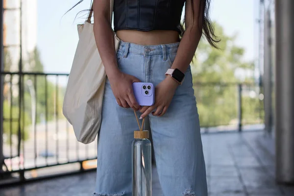 어깨에는 가방을 손에는 현대의 유리병을 유행적 도시의 거리에서 포즈를 취하는 — 스톡 사진