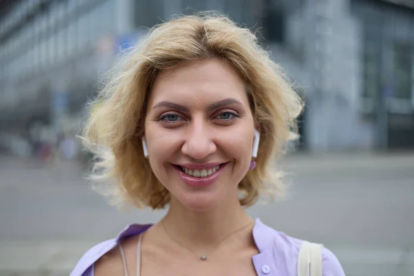 快乐的白人女人 在户外摆出愉快的笑容 在市中心散步时戴着无线耳机的友善的乌克兰女性形象 — 图库照片