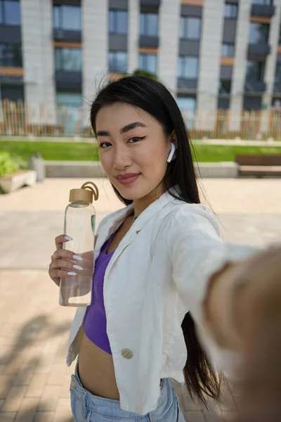 快乐的亚洲女人拿着一瓶水拍了一张自拍的照片 一个年轻貌美的越南妇女过着健康和可持续生活的画像 — 图库照片