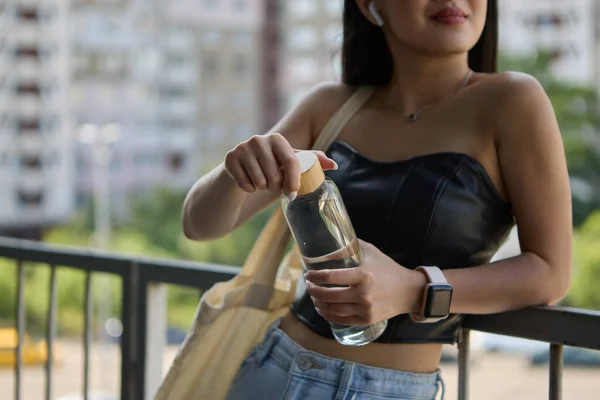年轻的亚洲女子打开了一瓶矿泉水 无法辨认的东南亚女人摘下瓶盖喝过滤过的水 — 图库照片