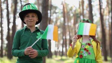 Cute kids celebrating St Patricks Day. Couple of white elementary age children dressed as leprechauns waving with Irish flags