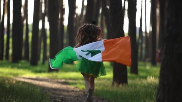 聖パトリックの日のお祝い スローモーションでアイルランドの国旗で走る愛らしい少女 — ストック動画