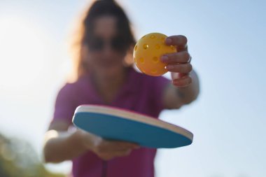 Pickleball oyuncusu yakın planda raketle top servis ediyor.