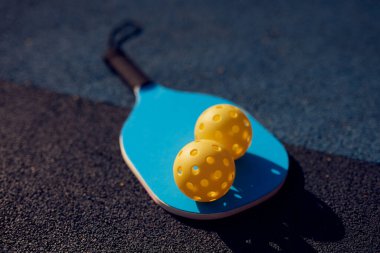 Raket ve delikli plastik toplar sahada yatıyor.