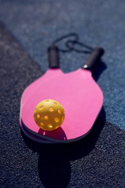 Pickleball raketleri ve sahada bir top.