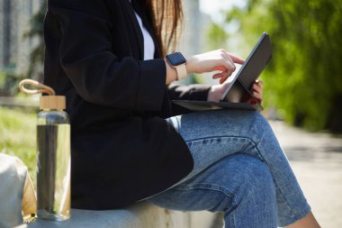 Genç bir kadın dışarıda oturmuş tablet bilgisayarına bakıyor..