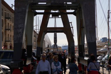 Genova 'daki Ligurian limanında eski vinç altında büyük bir turist grubu yürüyor. GENOVA - 1 Mayıs 2019