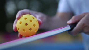 Pickleball oyuncusu yavaş çekim video klipinde raket ile topa servis yapmaya çalışıyor.