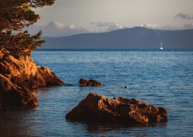 Hırvatistan 'da kayalık plajda gün batımı. Adriyatik deniz kıyısında güzel bir alacakaranlık 