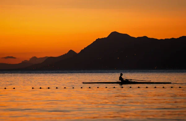 Beautiful sea wallpaper. Athlete rowing on kayak boat at sunset. Silhouette of a sportsman kayaking in the sea at dusk