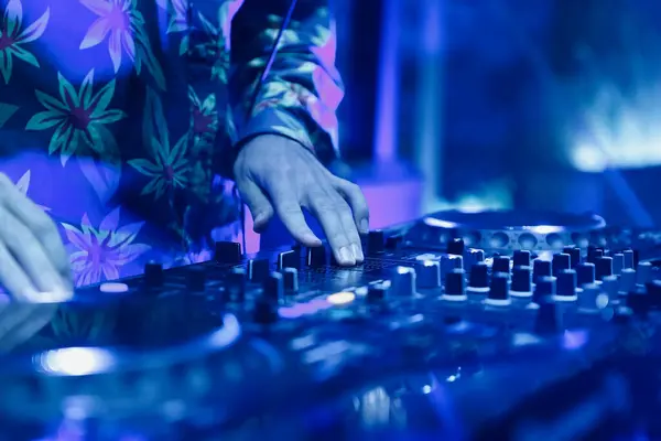 stock image Club DJ playing techno music in bright blue lights. Professional disk jokey mixing musical tracks with a sound mixer