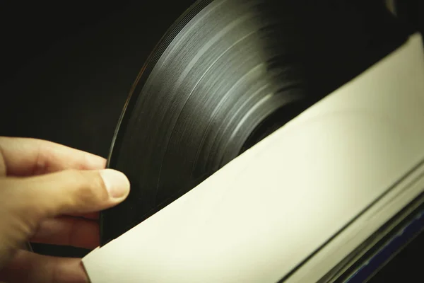 Vinyl collector takes a vinyl record out of paper envelope to listen to the music.