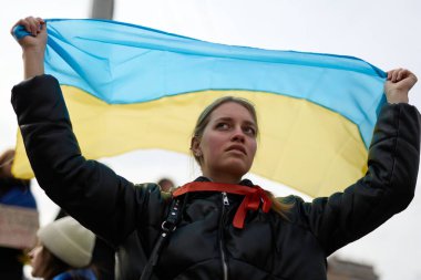 Genç Ukraynalı vatansever barışçıl bir mitingde Ukrayna bayrağını başının üzerinde tutuyor. Kyiv - 3 Mart 2024
