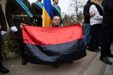 Ukrayna milliyetçilerinin kırmızı ve siyah bayrağını taşıyan asker, Cennetin Kahramanları Günü 'nde özgürlük savaşının sembolü olarak. Kyiv - 20 Şubat 2024