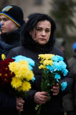 Ukraynalı kadın Cennetin Kahramanları Günü 'nde düzenlenen törende vatansever mavi ve sarı bir buket çiçek tutuyor. Kyiv - 20 Şubat 2024