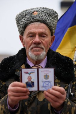 Geleneksel Kozak şapkalı kıdemli asker gururla Ukrayna milliyetçi kimlik belgesini gösteriyor. Kyiv - 20 Şubat 2024