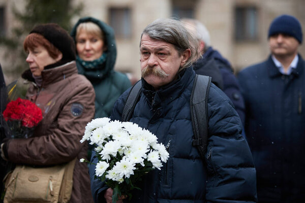 Senior Ukrainian man with a bouquet of flowers on the honoring ceremony dedicated to the fallen activists of Maidan on the Day of the Heroes of the Heavenly Hundred. Kyiv - 20 February, 2024