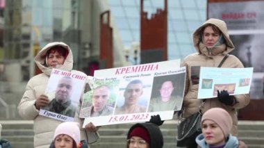 Ukraynalı kadınlar, 25 Şubat 2024 'te Kyiv' de düzenlenen mitingde kayıp akrabalarının portreleriyle birlikte bir pankart taşıyorlar.