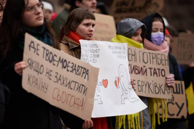 Kentin idari ofis girişinde askeri bütçenin artırılması için düzenlenen mitingde pankart taşıyan bir grup gösterici görülüyor. Kyiv - 17 Şubat 2024