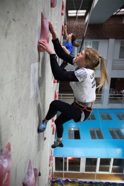 Genç bayan tırmanışçı, kapalı alanda tırmanma yarışmasında hız duvarının tepesine tırmanır. Kyiv - 6 Mart 2024