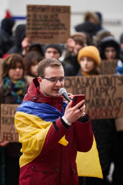 Genç Ukraynalı vatansever, yolsuzlukla mücadele ve askeri bütçenin artırılması için halka açık bir gösteride mikrofonda konuşuyor. Kyiv - 10 Şubat 2024