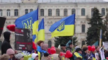 Ulusal bayrakları rüzgarda sallanan bir grup Ukraynalı. 16 Mart 2024 'te Kyiv' deki Meydan Nezalezhosti Meydanı 'nda büyük halk gösterisi