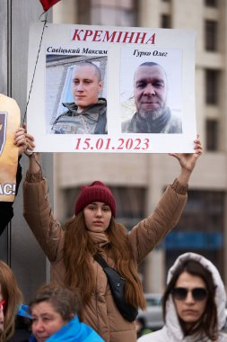 Ukraynalı genç bir insan, Ukrayna Silahlı Kuvvetleri 'nin askerlerinin resimlerini taşıyan bir pankartıyla halka açık bir gösteride poz veriyor. Kyiv - 16 Mart 2024