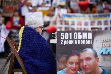 Küçük Ukraynalı çocuk boş masada, elinde Rus tutsağı olan anne ve babasının portresiyle oturuyor. Kyiv - 16 Mart 2024