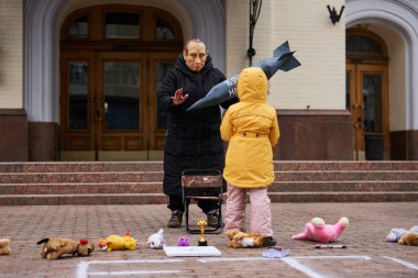 Actor in mask of vladimir putin threatening the Ukrainian child with a bomb at the art performance dedicated to the anniversary of russian attack on Mariupol Drama Theatre. Kyiv - 17 March,2024 clipart