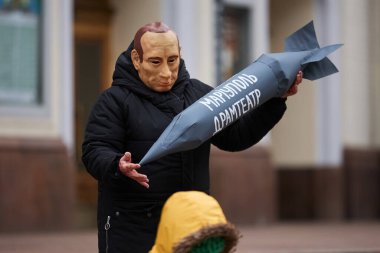 Actor wearing mask of putin holds a bomb with the writing 