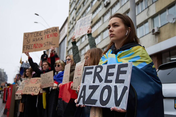 Young woman wearing flag of Donbas region of Ukraine and holding a sign "Free Azov" on a public demonstration for release of captured defenders of Mariupol. Kyiv - 17 March,2024