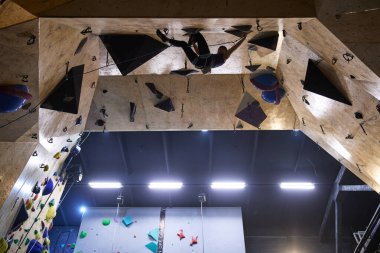 Profesyonel bir atlet emniyet ipi ve koşum takımına bağlı olarak yüksek duvara tırmanıyor. Kyiv - 10 Mart 2024