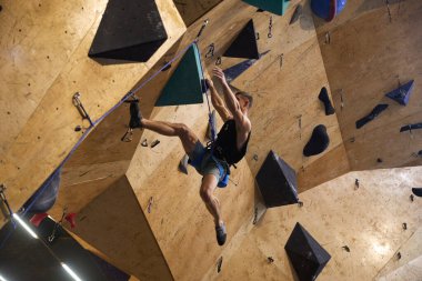 Dağcı, çokgen bir tırmanma duvarında asılı duran güvenlik ipine bağlı. Kyiv - 10 Mart 2024