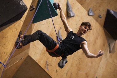 Duvarda asılı duran neşeli Ukraynalı dağcı emniyet kemeri ve ip takıyor. Kyiv - 10 Mart 2024